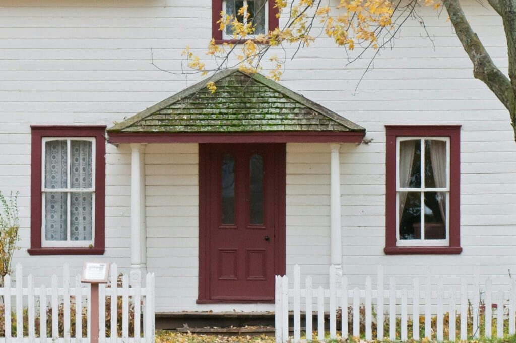 Picturesque traditional house with autumn foliage and a white picket fence in London, Ontario.